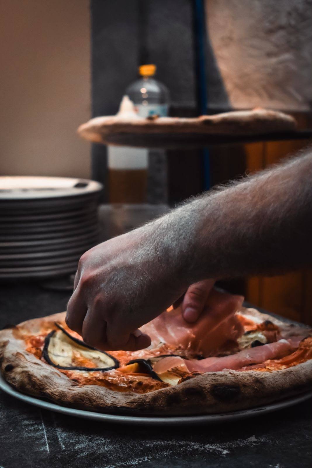 Une pizza garnie de jambon cru et d'aubergines, à la sortie du four